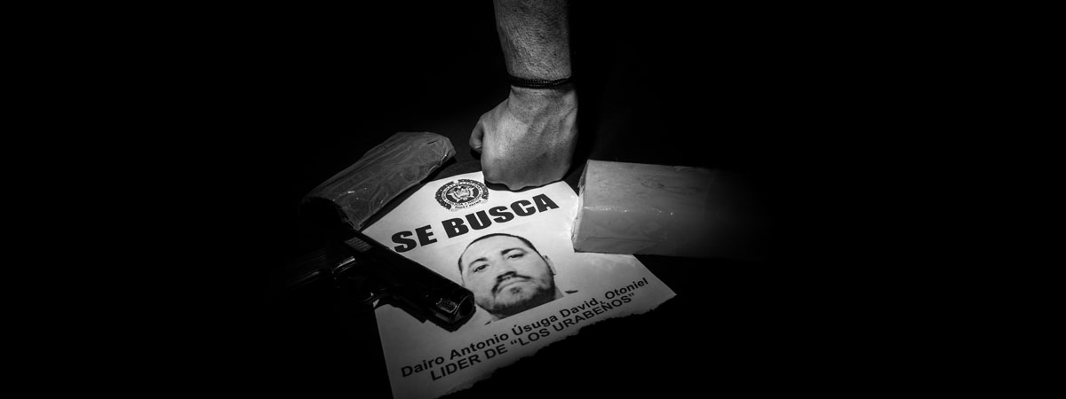 Image of a law enforcement officer with his fist on a wanted poster in Spanish